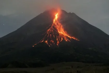 Pemandangan puncak Gunung Merapi di pagi hari, diselimuti kabut tipis dengan asap vulkanik yang terus-menerus keluar dari kawahnya